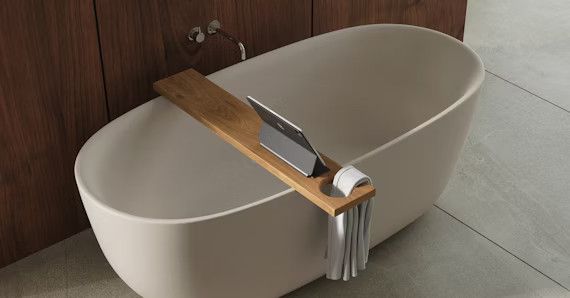 Eine leere Badewanne in Beige mit einer Badewannenbrücke aus Holz.